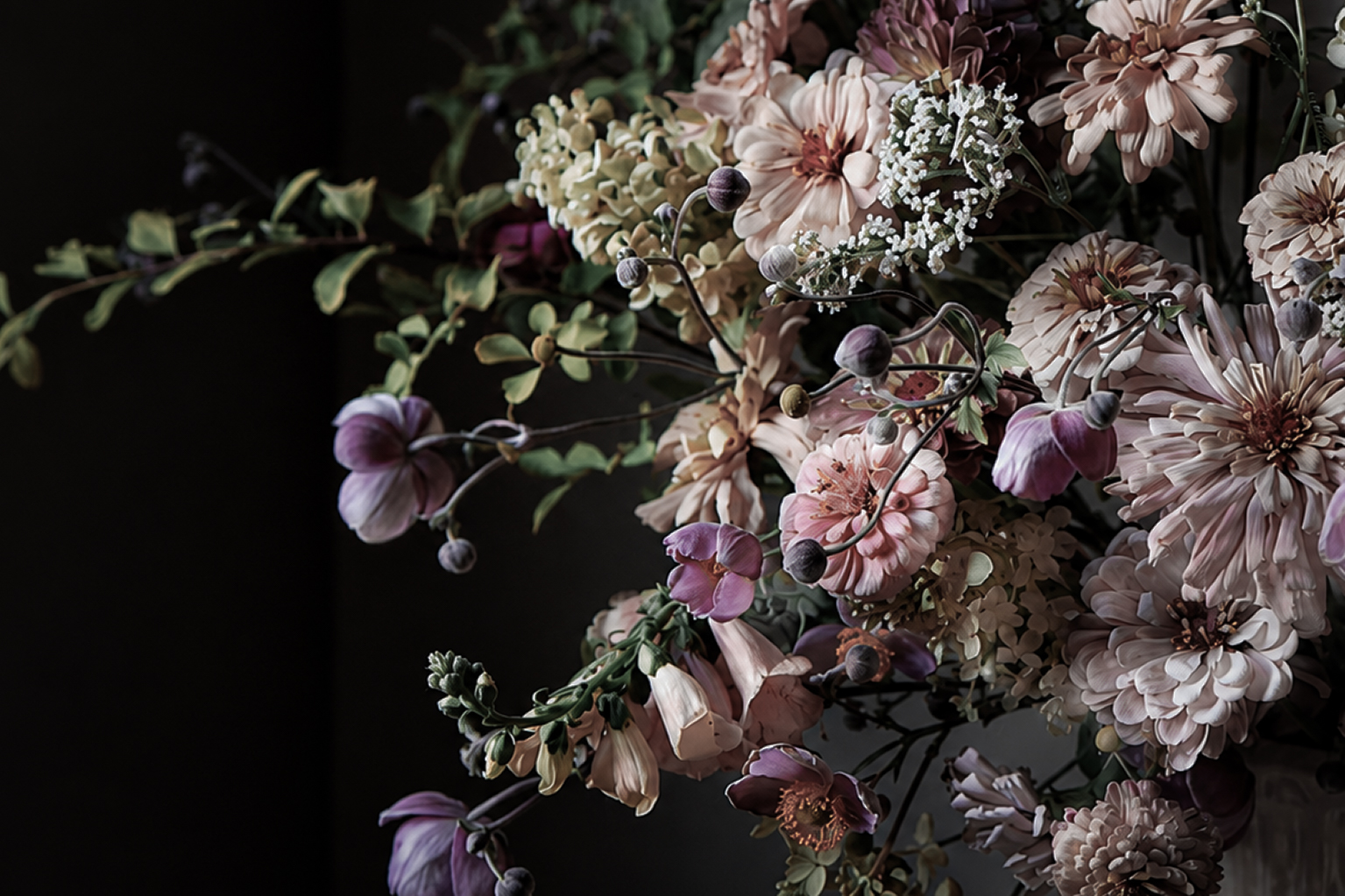 Flower Rill floral arrangement with pale pink flowers and arching purple stems against a dark background